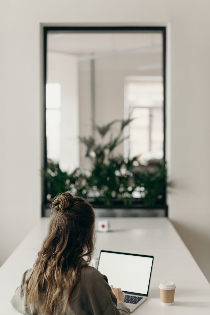 Une femme qui travaille sur son mac dans une belle pièce avec un miroir